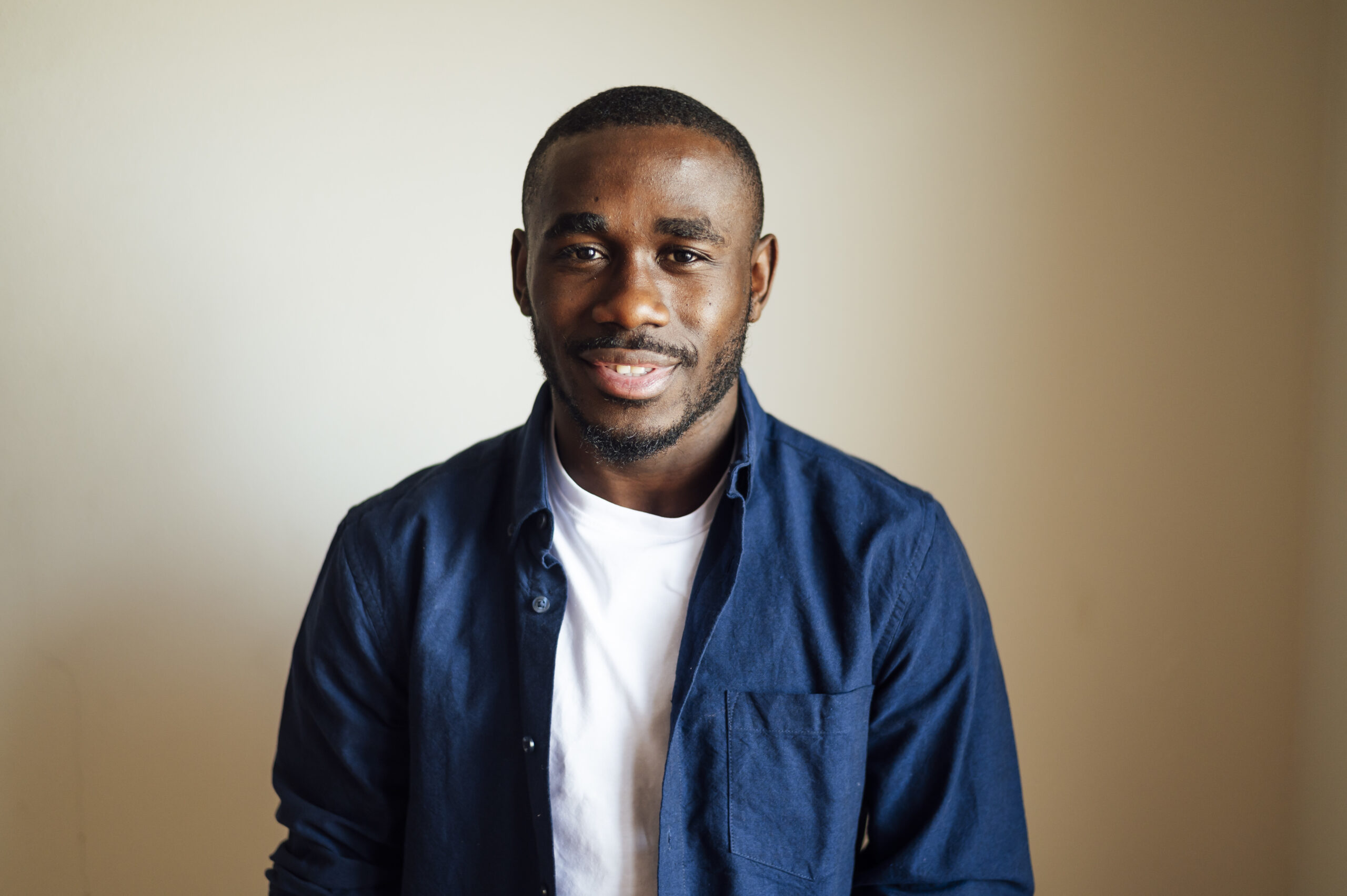 closeup shot of a smiling black male in front of a brown background happiness concept